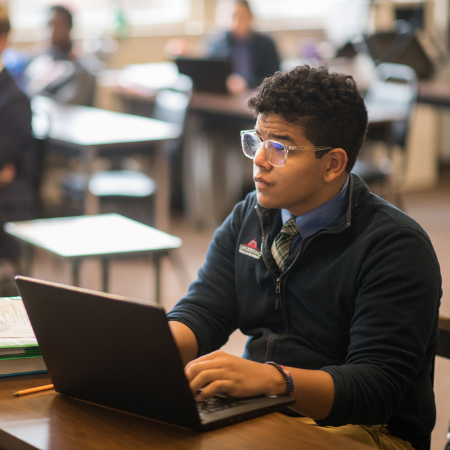 A high school student taking notes on a laptop at Dayspring Christian Academy.